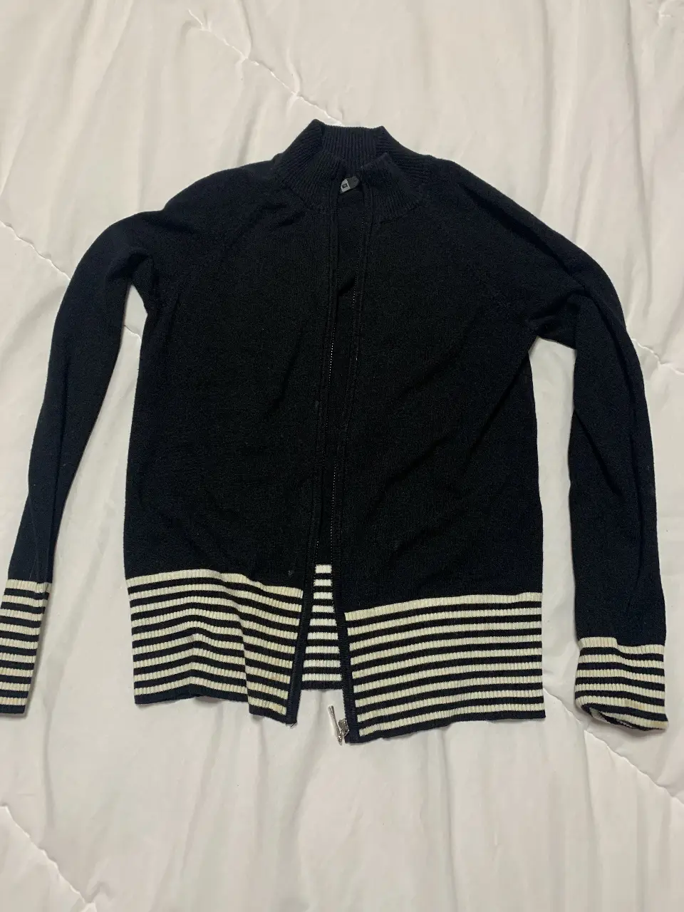 Sweater de mujer negro con cierre y detalles a rayas blancas en puños y cintura. Ideal para un look casual y abrigado.