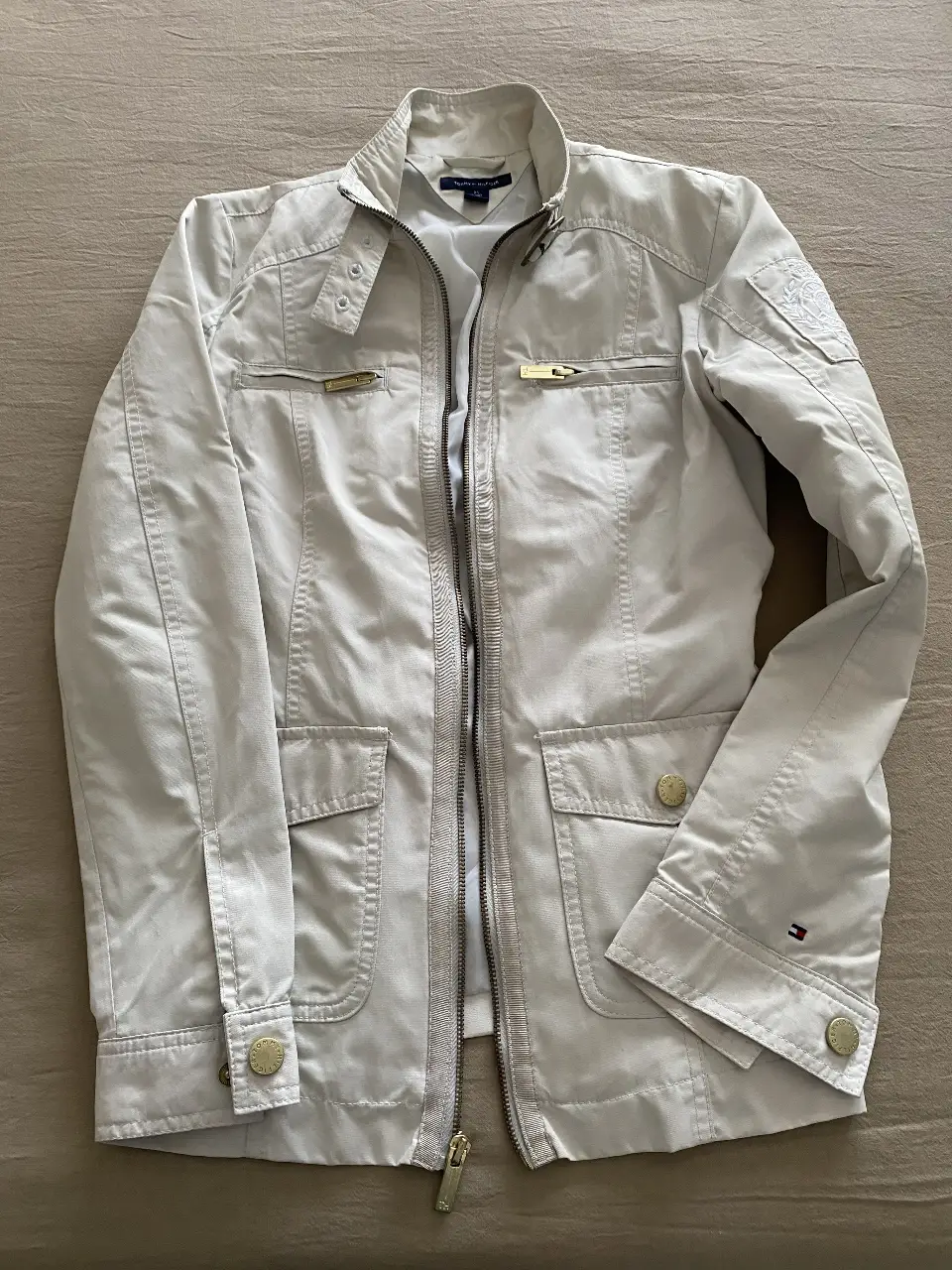 Campera Tommy Hilfiger color crudo, con cierre y bolsillos. Talle XS. Ideal para un look casual y elegante.