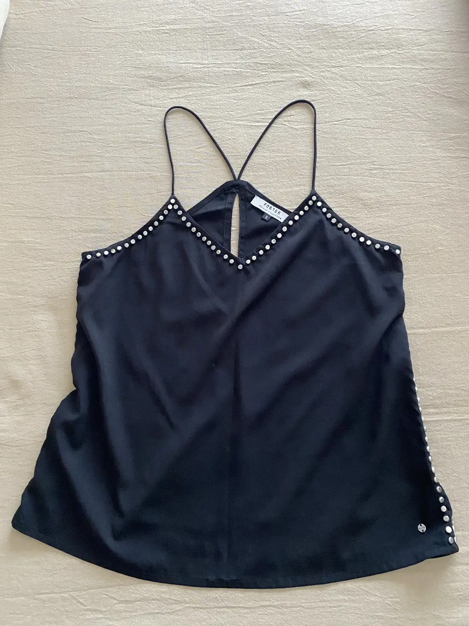 Top negro con tirantes finos y detalles de tachas plateadas. Ideal para una salida o fiesta.
