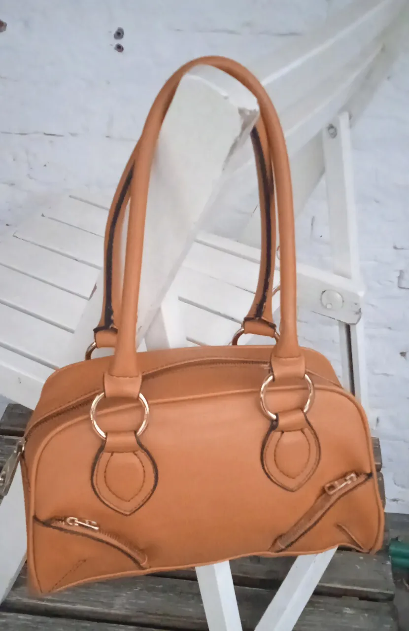 Cartera de cuero sintético, de la marca Mango,  color caramelo con  manijas cortas y detalles metálicos en color dorado.
En perfecto estado, muy poco uso. Súper espaciosa.