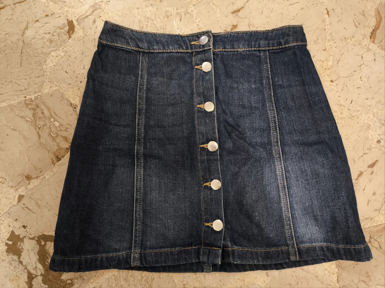 Minifalda de jean azul oscuro con botones frontales. Talle 36 EUR, 8 US. Ideal para un look casual y moderno.