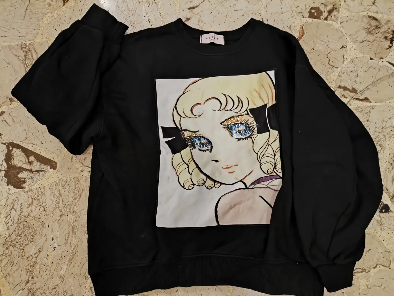 Buzo de cuello redondo negro con estampado de un rostro de anime. La prenda es de la marca Sucré Seoul. Sin uso!