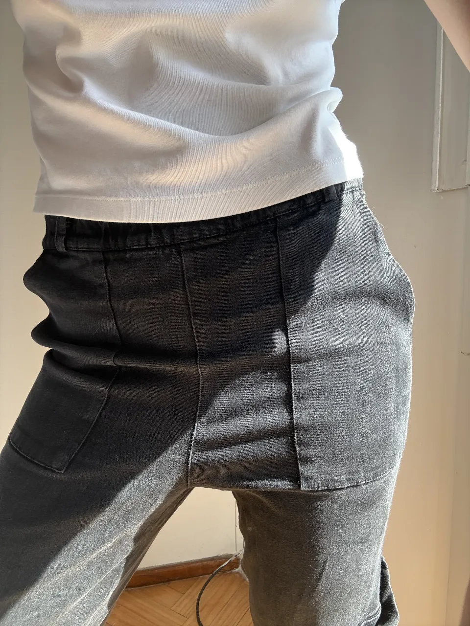 Pantalón cargo de jean gris oscuro, tiro alto con elástico en la cintura. Diseño moderno con bolsillos utilitarios y costuras marcadas. Ideal para un look casual y canchero.