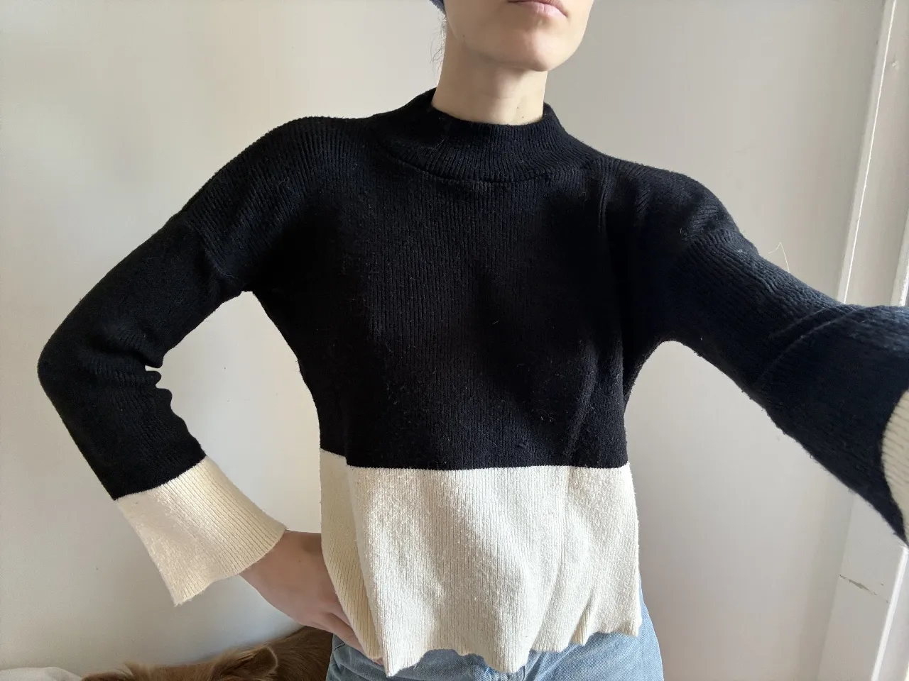 Sweater de cuello alto, manga larga y corte recto. Diseño bicolor en negro y crudo, con puños acampanados. Ideal para un look casual y moderno.