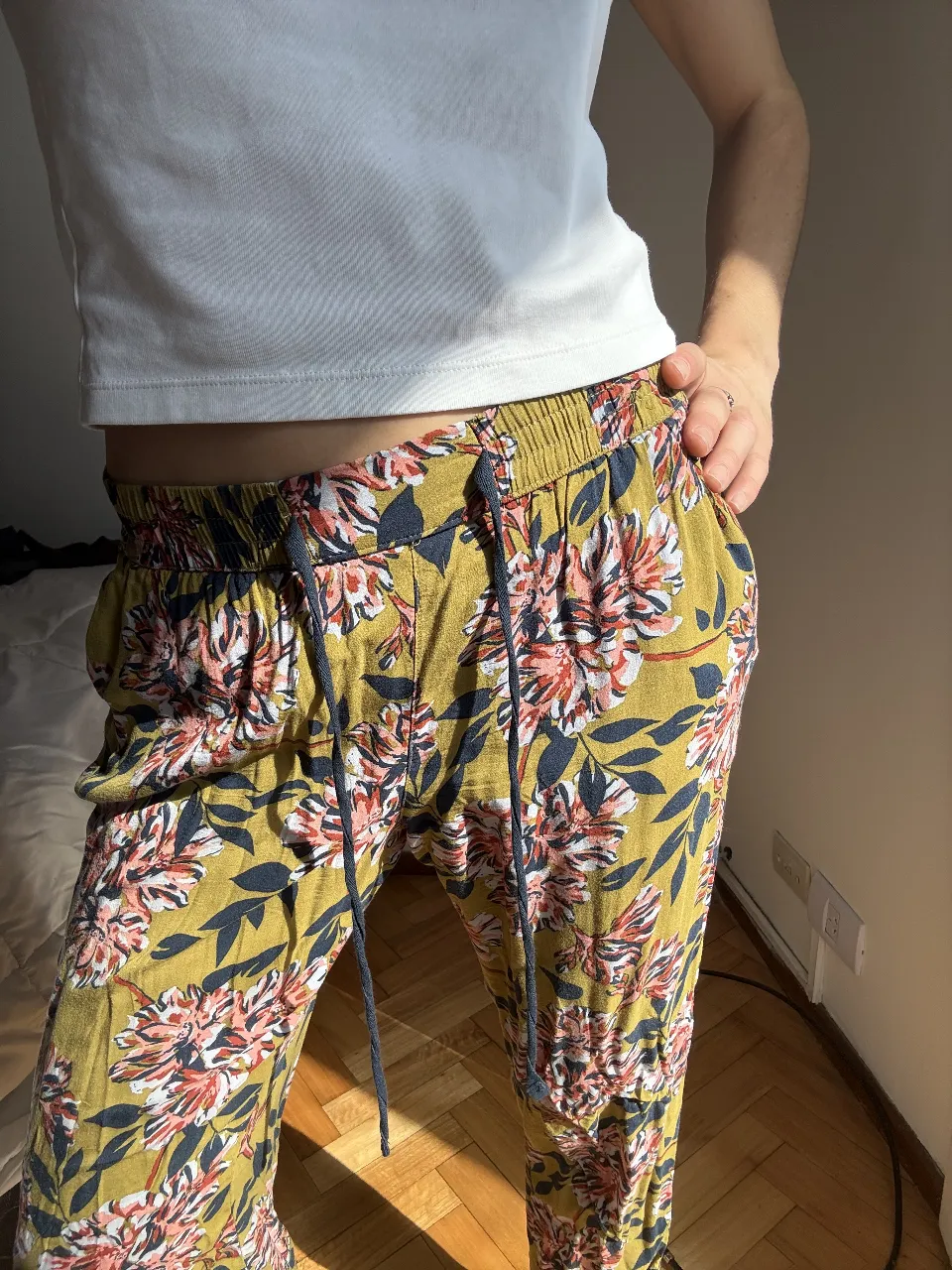 Pantalón de tela liviana con estampa floral vibrante en tonos verdes, rosas y azules. Posee cintura elastizada con cordón ajustable y bolsillos laterales. Ideal para un look relajado y con onda.