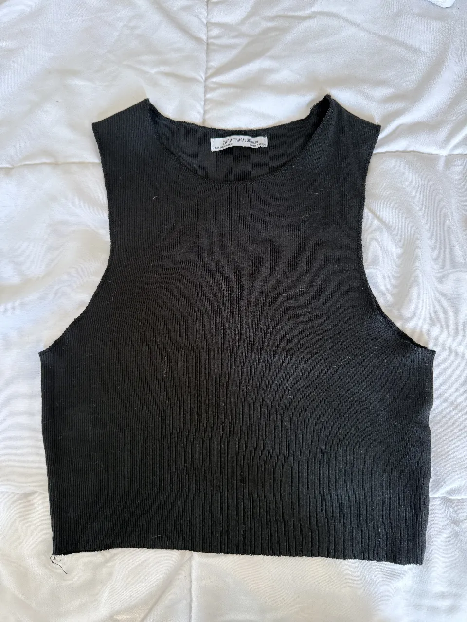 Top negro de tejido acanalado, súper canchero y versátil. Ideal para combinar con todo y armar looks modernos. Queda genial con jeans, shorts o polleras.