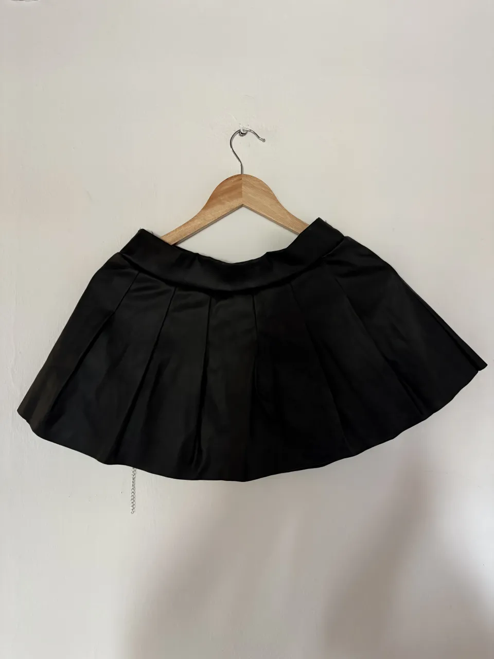 Pollera negra corta, con tablas y detalle de cadena. Ideal para looks cancheros y de fiesta.