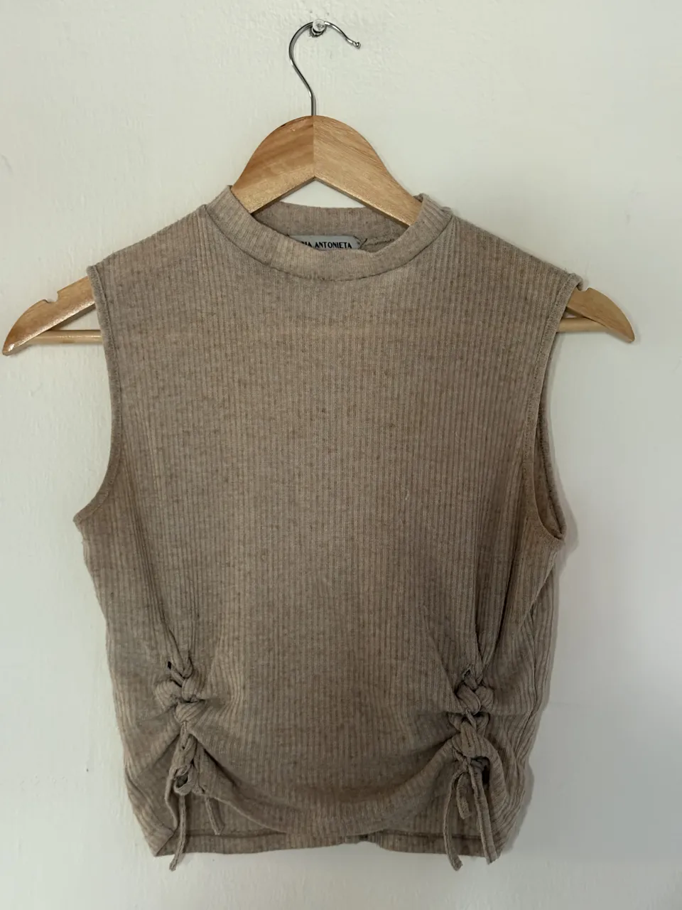 Musculosa de tejido acanalado color tiza, con detalles de nudos y tiras en los laterales. Ideal para un look casual y moderno.