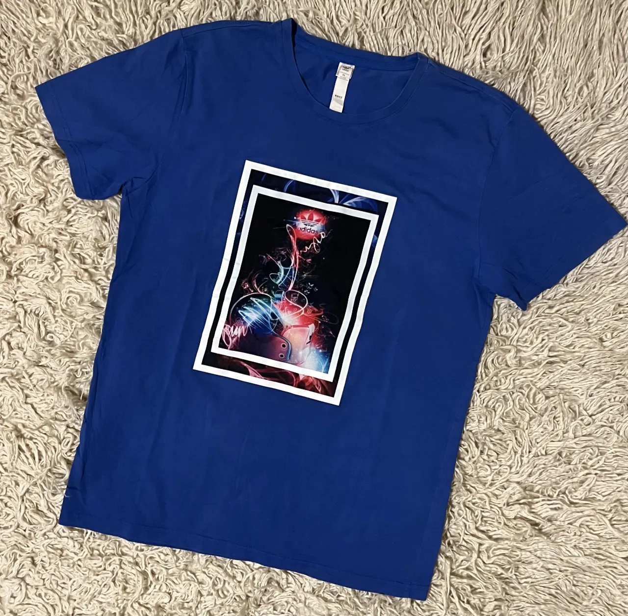 Remera azul Adidas de manga corta. con estampa gráfica en el frente.