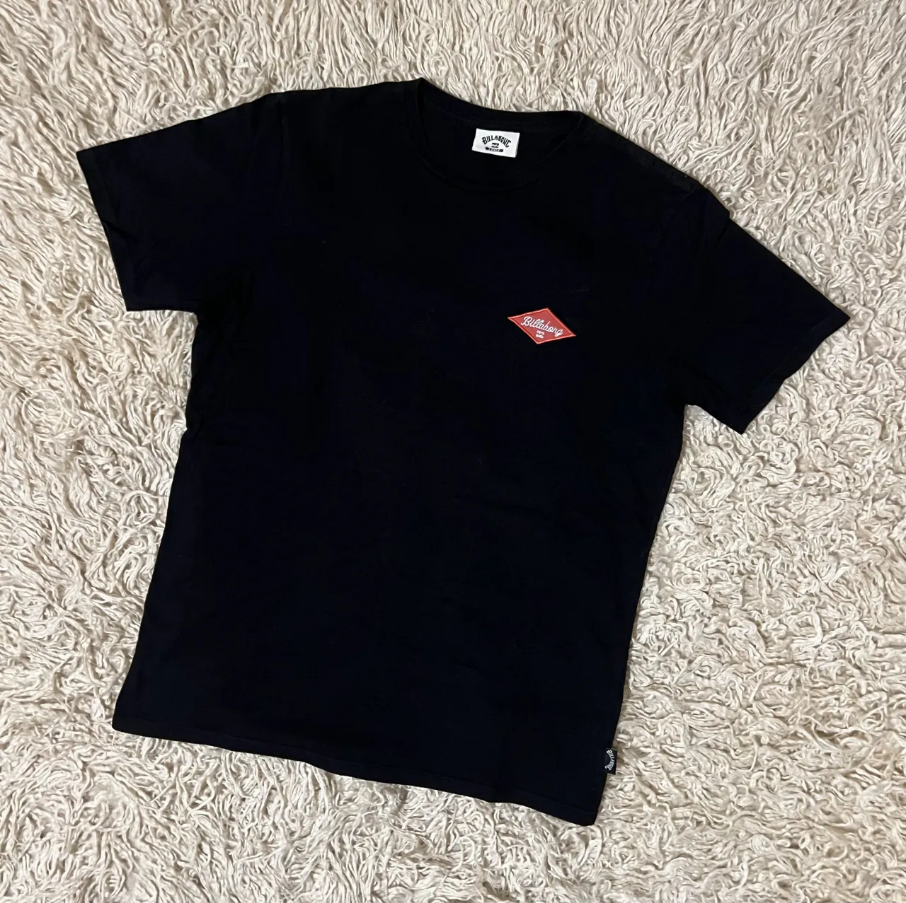 Remera negra de manga corta con logo de Billabong bordado en forma de rombo en el frente.