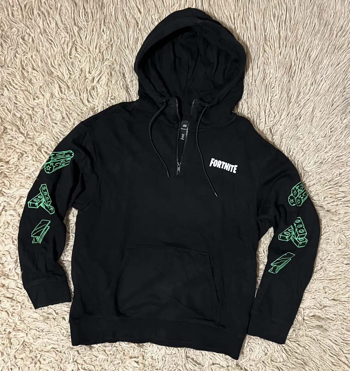 Buzo negro con capucha y cierre partial. Estampado de Fortnite en el frente y diseño de llama esquelética en la espalda. Mangas con detalles de bloques de construcción verdes. Sisa 57 Cm - Largo 72 Cm 