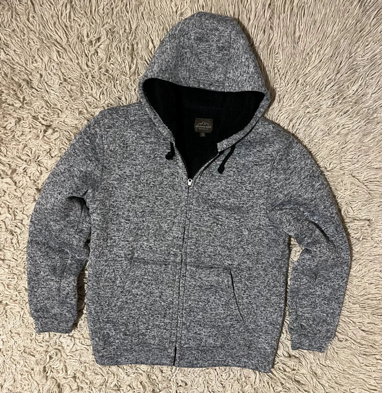 Campera gris con capucha y cierre completo. Posee dos bolsillos frontales tipo canguro. El interior es de sherpa negro. Sisa 58 Cm - Largo 73 Cm 