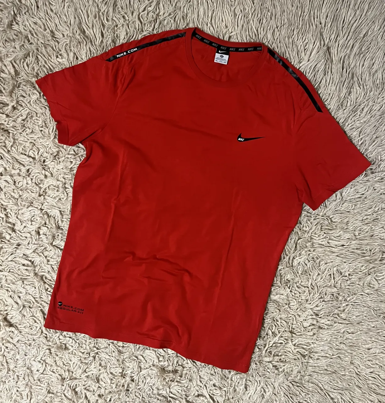Remera roja de manga corta con logo de Nike y detalles de la marca en los hombros y en la manga izquierda. Cuello redondo. Sisa 59 Cm - Largo 80 Cm 