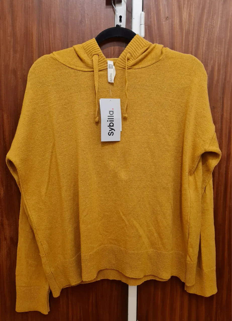 Buzo de mujer color mostaza con capucha, de la marca Sybilla. Talle M. Nuevo con etiqueta! Suave al tacto, abrigado pero ligero, perfecto para entretiempo o para usar en capas durante el invierno. Ideal para un look casual. 