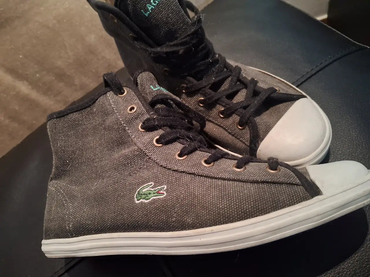 Zapatillas Lacoste de lona gris oscuro con suela blanca y el logo de la marca. Talle 35.5 EUR, 3 UK, 5 USA. Ideales para un look casual y cómodo. Impecables. Un solo uso.