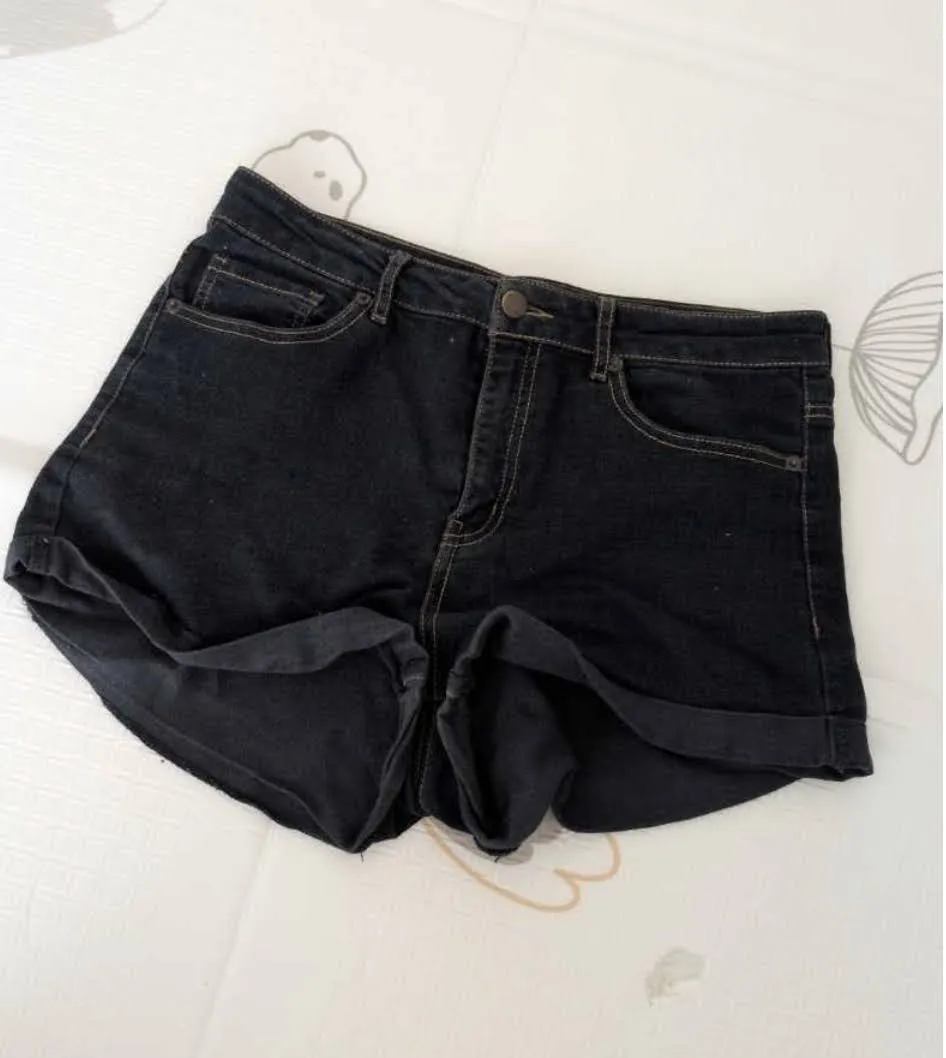 Shorts de jean azul oscuro con costuras doradas y dobladillo en los bajos. 