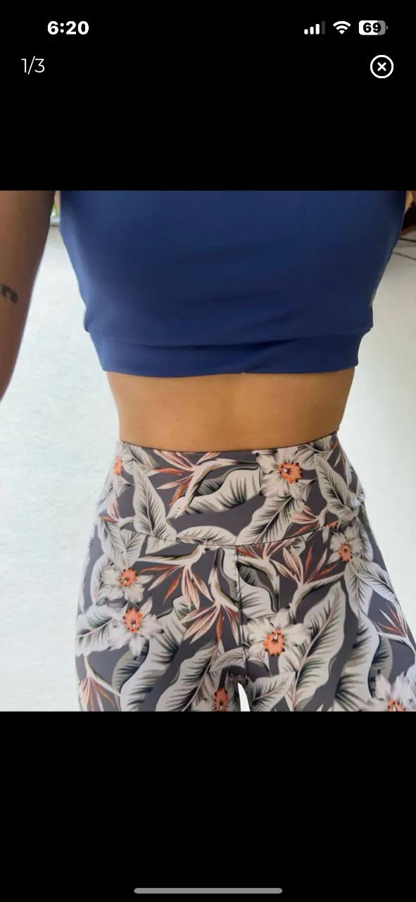 Calzas deportivas con estampado floral en tonos grises, blancos y detalles en naranja. Perfectas para tus entrenamientos o para un look casual y cómodo.