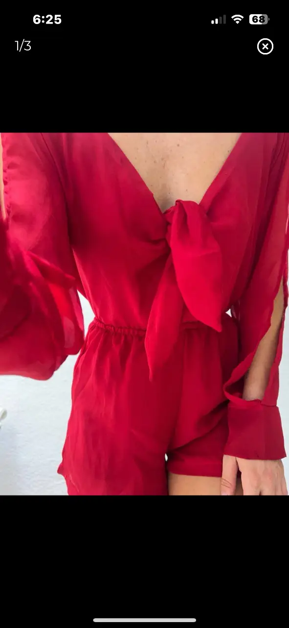 Mono corto rojo con escote en V y detalle de lazo. Mangas largas con aberturas en los hombros y puños. Ideal para fiestas y eventos.