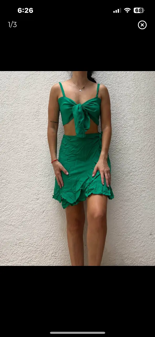 Conjunto de dos piezas verde, ideal para el verano. El top es estilo corpiño con un lazo en el centro y breteles finos. La pollera es corta, con volados en el borde.