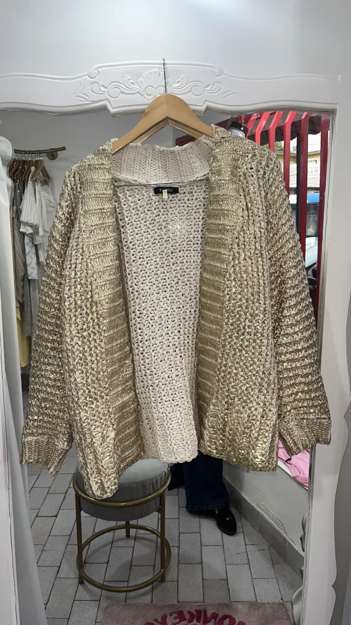 Cardigan tejido color dorado y crudo. Posee mangas largas y es abierto al frente.