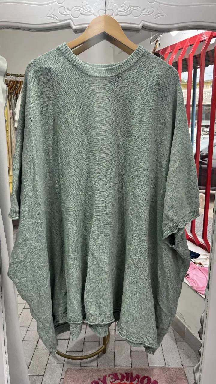 Poncho tejido de color verde claro con cuello redondo y mangas cortas.