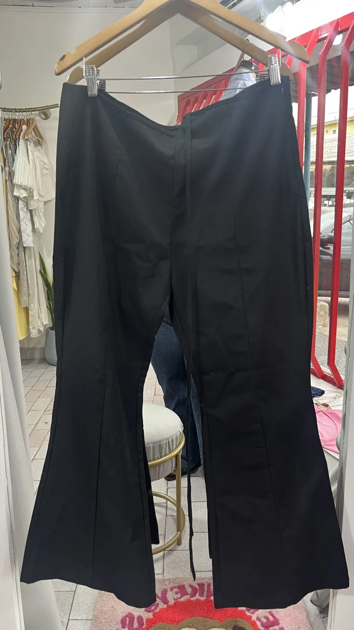 Pantalón negro con lazos en la cintura y corte acampanado en la parte inferior. tiene roto en la tira de la cintura vino así cuando lo pedí 