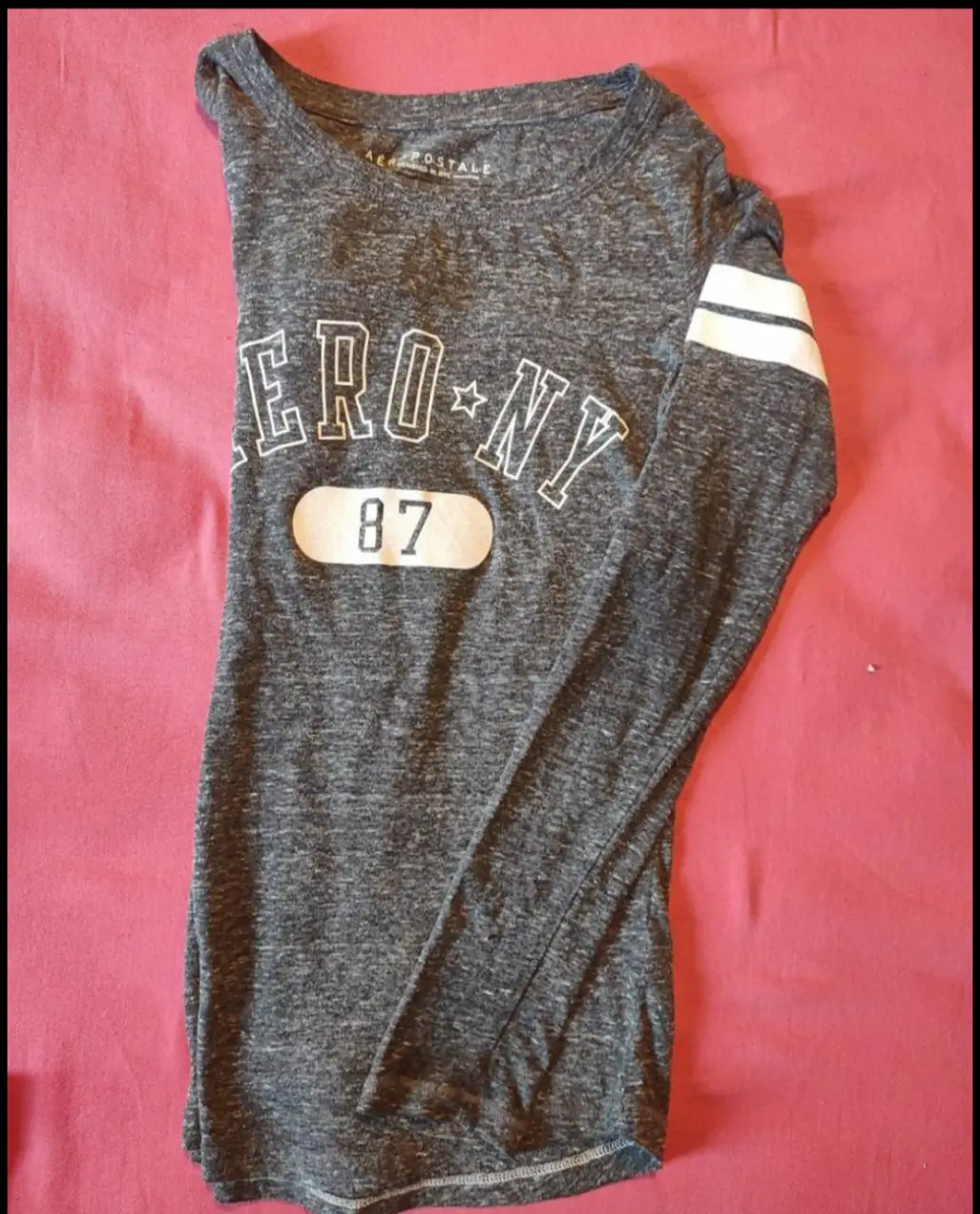 Remera manga larga gris con estampado "ERO-NY 87" en blanco. Estilo deportivo y casual, ideal para un look urbano.