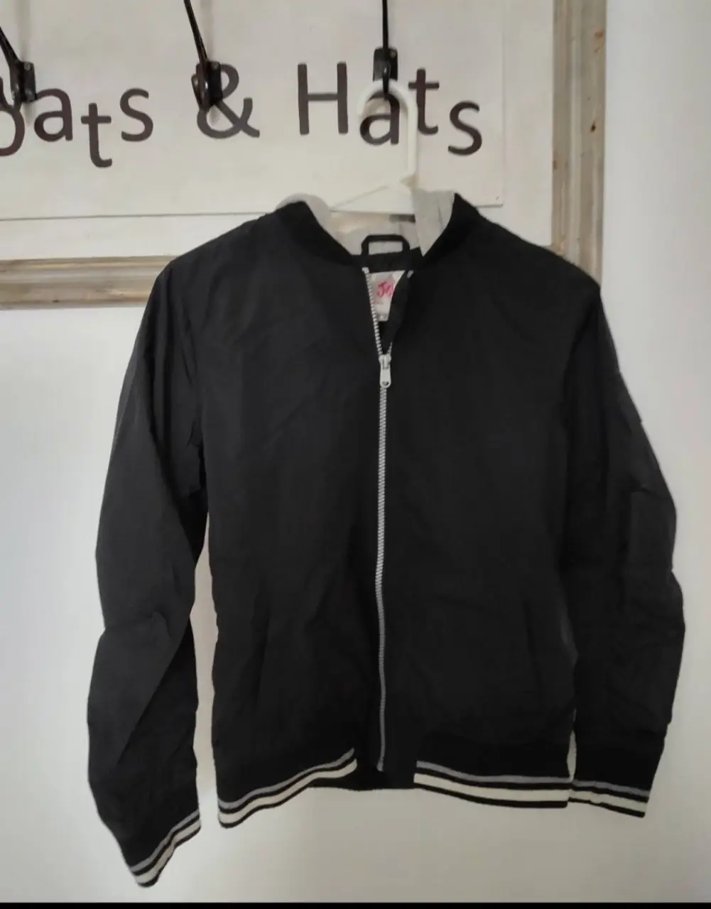 Campera bomber negra con capucha gris. Ideal para un look casual y urbano. Posee cierre frontal y detalles en los puños y cintura.
