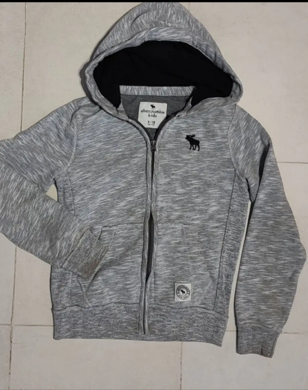 Buzo con cierre y capucha para niño, de la marca Abercrombie Kids. Color gris jaspeado, ideal para un look casual y abrigado.