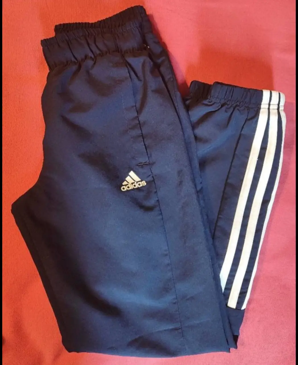 Pantalón deportivo Adidas azul marino con las tres tiras blancas en el lateral. Ideal para entrenar o para un look casual.