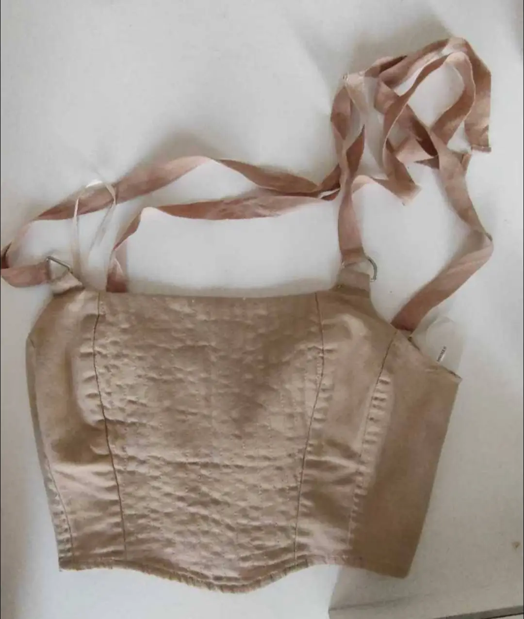 Top corset color crudo con tiras para atar al cuello y espalda. Ideal para un look elegante y moderno.