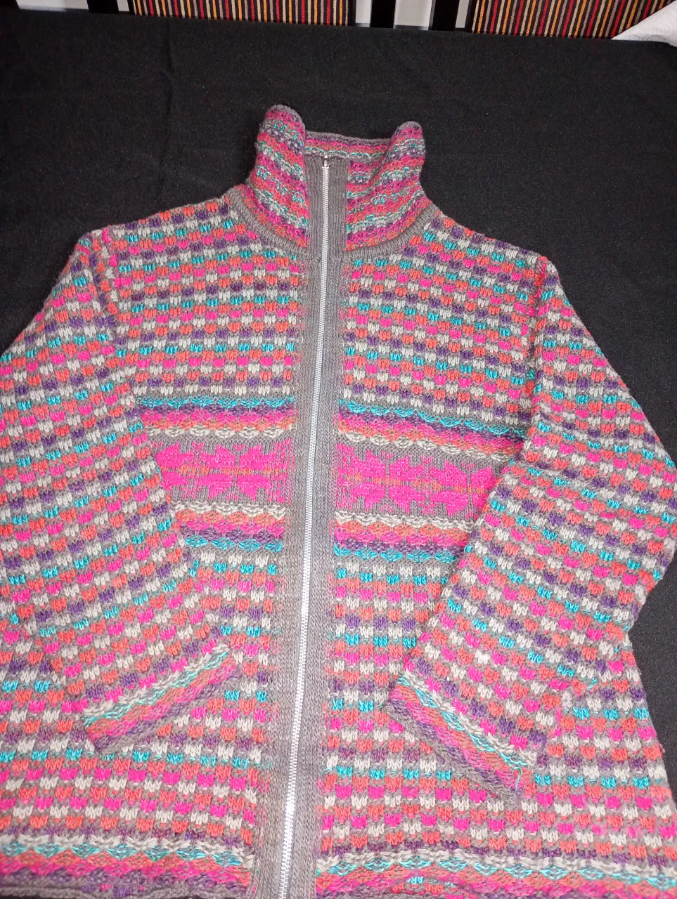 Sweater de mujer con cierre y cuello alto, tejido con diseño geométrico en tonos rosa, violeta, gris y celeste. Ideal para el invierno.