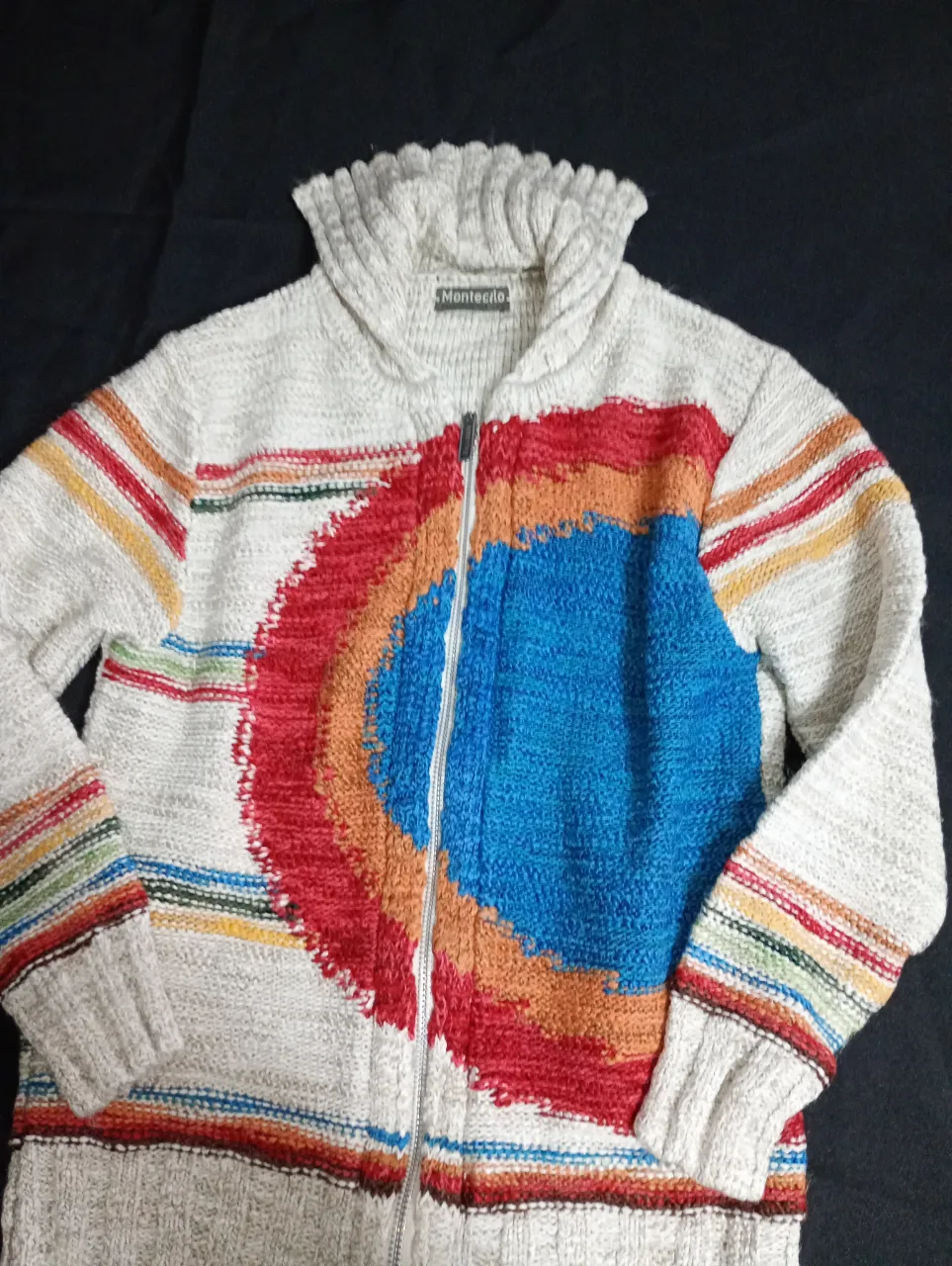 Sweater con cierre y cuello alto, con diseño multicolor en el frente. Ideal para un look casual y abrigado.