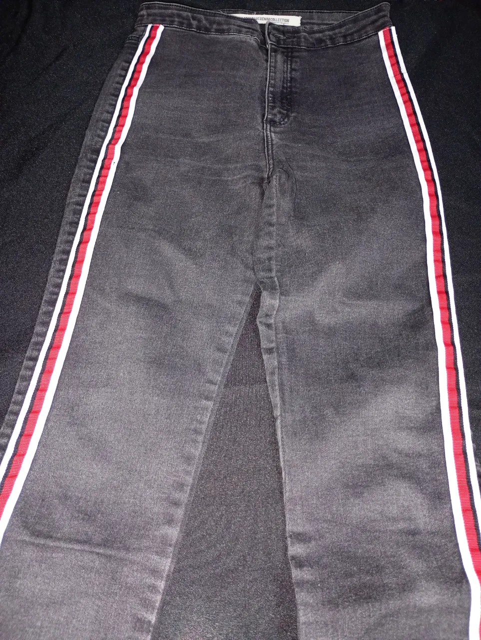 Jeans de mujer tiro alto, color negro con detalles en blanco y rojo en los laterales. Un clásico moderno para cualquier ocasión.