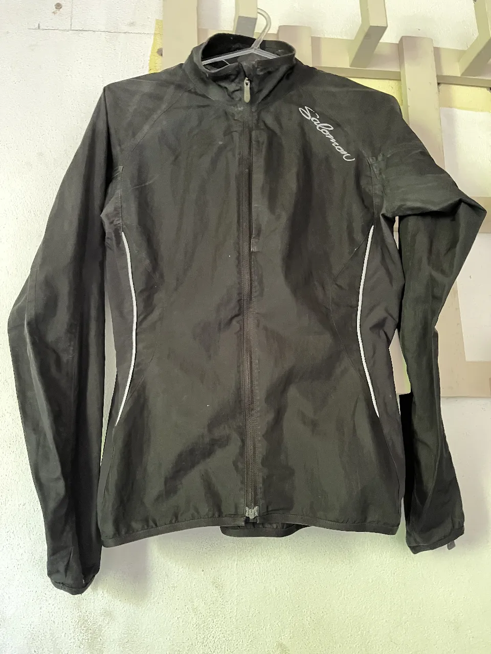Campera deportiva negra Salomon. Cierre completo al frente y bolsillos con cierre. Detalles en los puños. Bolsillo en pecho. 