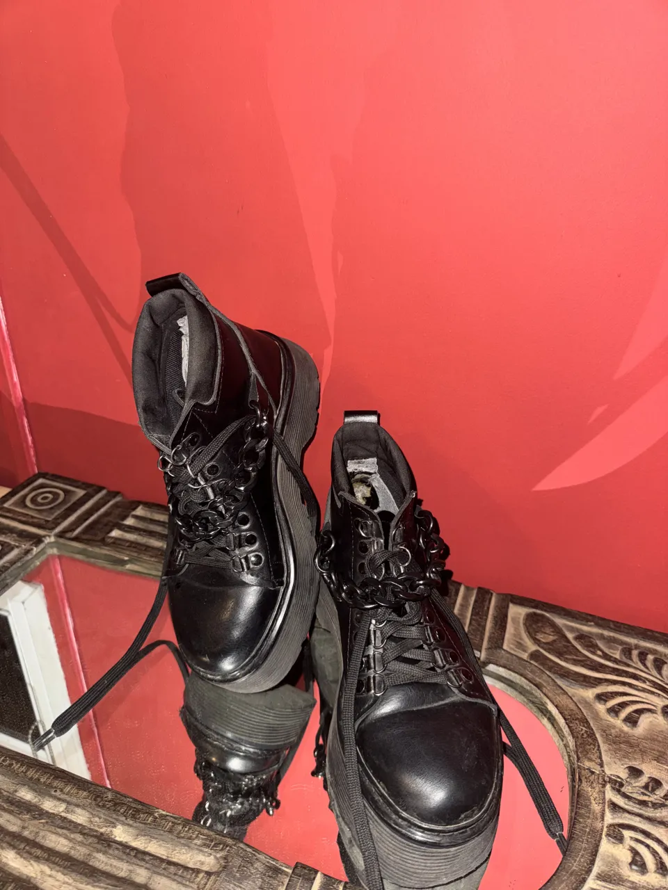 Botas negras con plataforma y cordones. Tienen cadenas decorativas en los cordones y ojales metálicos.