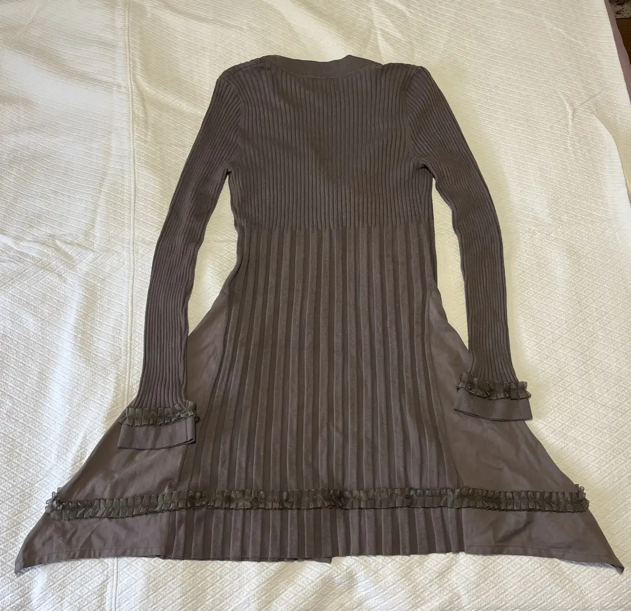 Vestido midi de mujer, color marrón, con mangas largas y detalles de volados en los puños y el bajo. Tiene un diseño plisado en la parte delantera y un botón para cerrar. Ideal para un look elegante y sofisticado.