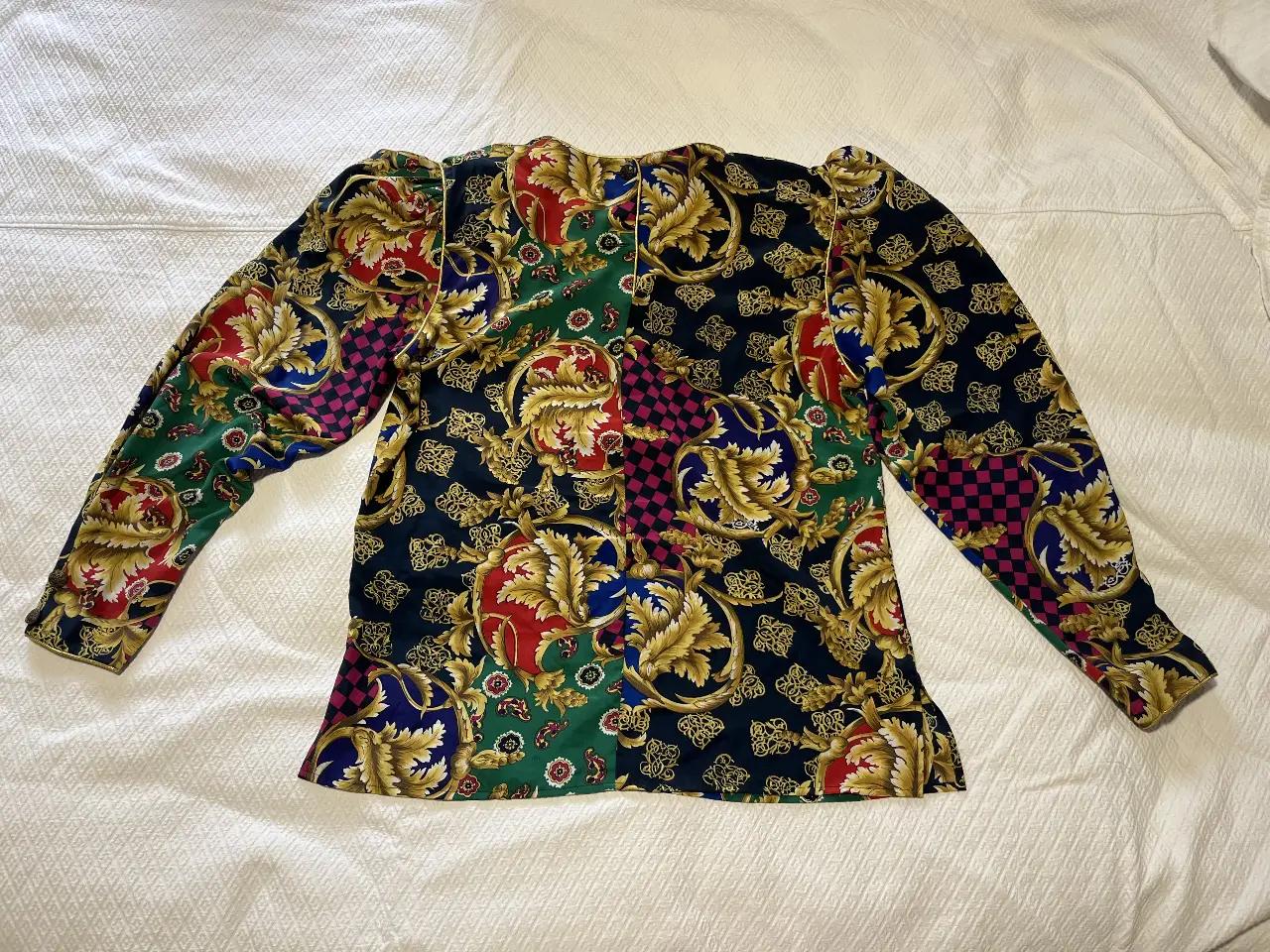 Blusa vintage de manga larga con estampado barroco en tonos rojo, verde, azul y dorado. Cuello redondo y detalles dorados en los bordes. Ideal para un look elegante y retro.