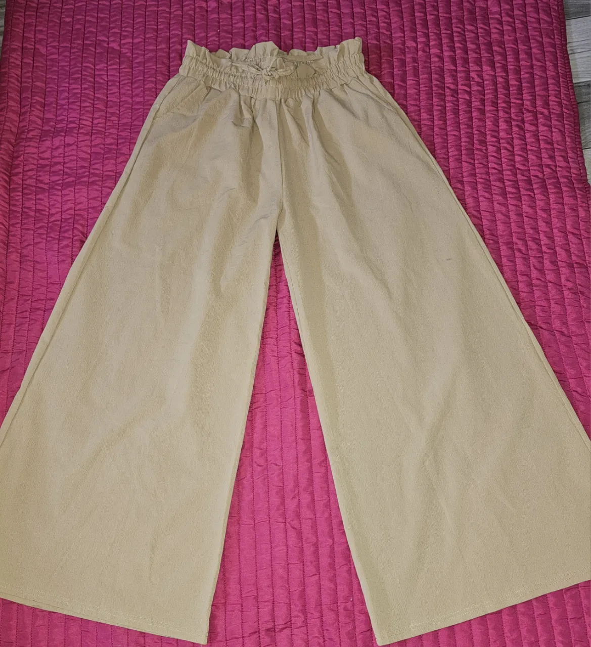 Pantalón de color beige con cintura elastizada y lazo.