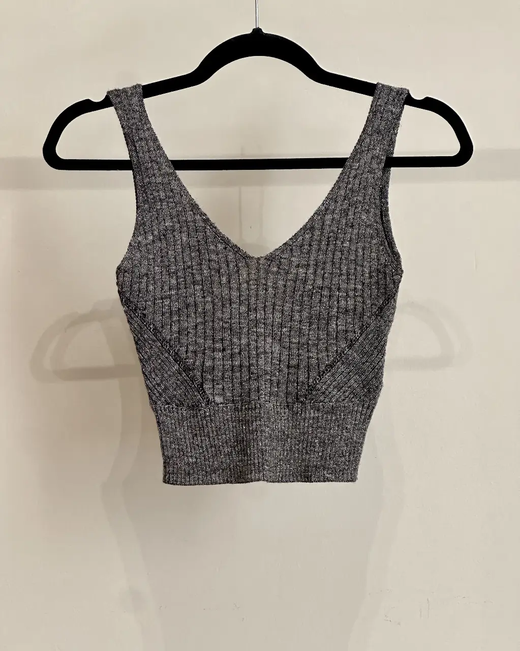 Top tejido de punto gris con brillitos, escote en V y detalle en la cintura. Ideal para un look casual y moderno. Excelente estado.