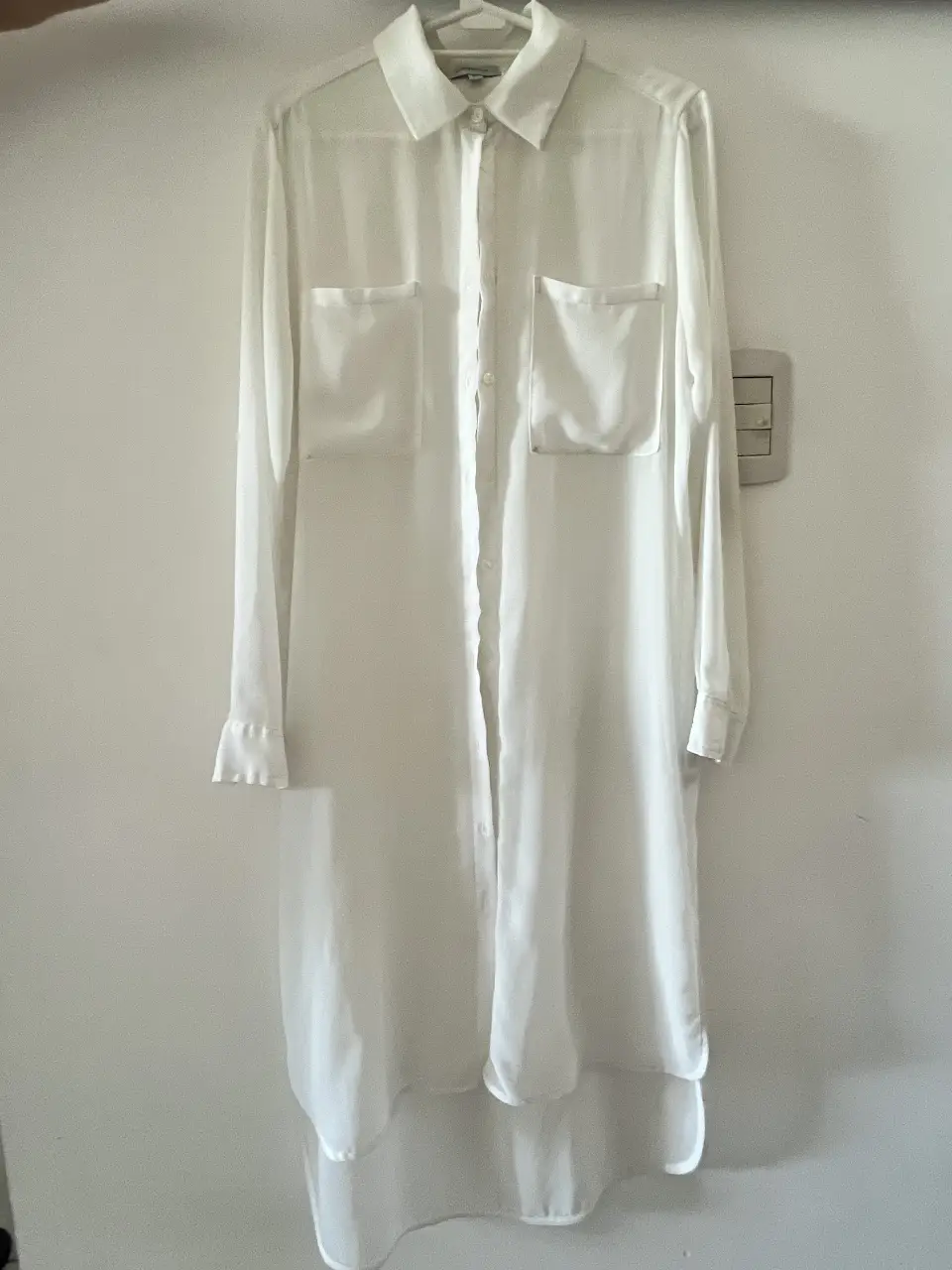 Camisa larga blanca de mujer, con cuello clásico y dos bolsillos delanteros. Ideal para un look elegante y versátil. Kosiuko, talle ÚNICO