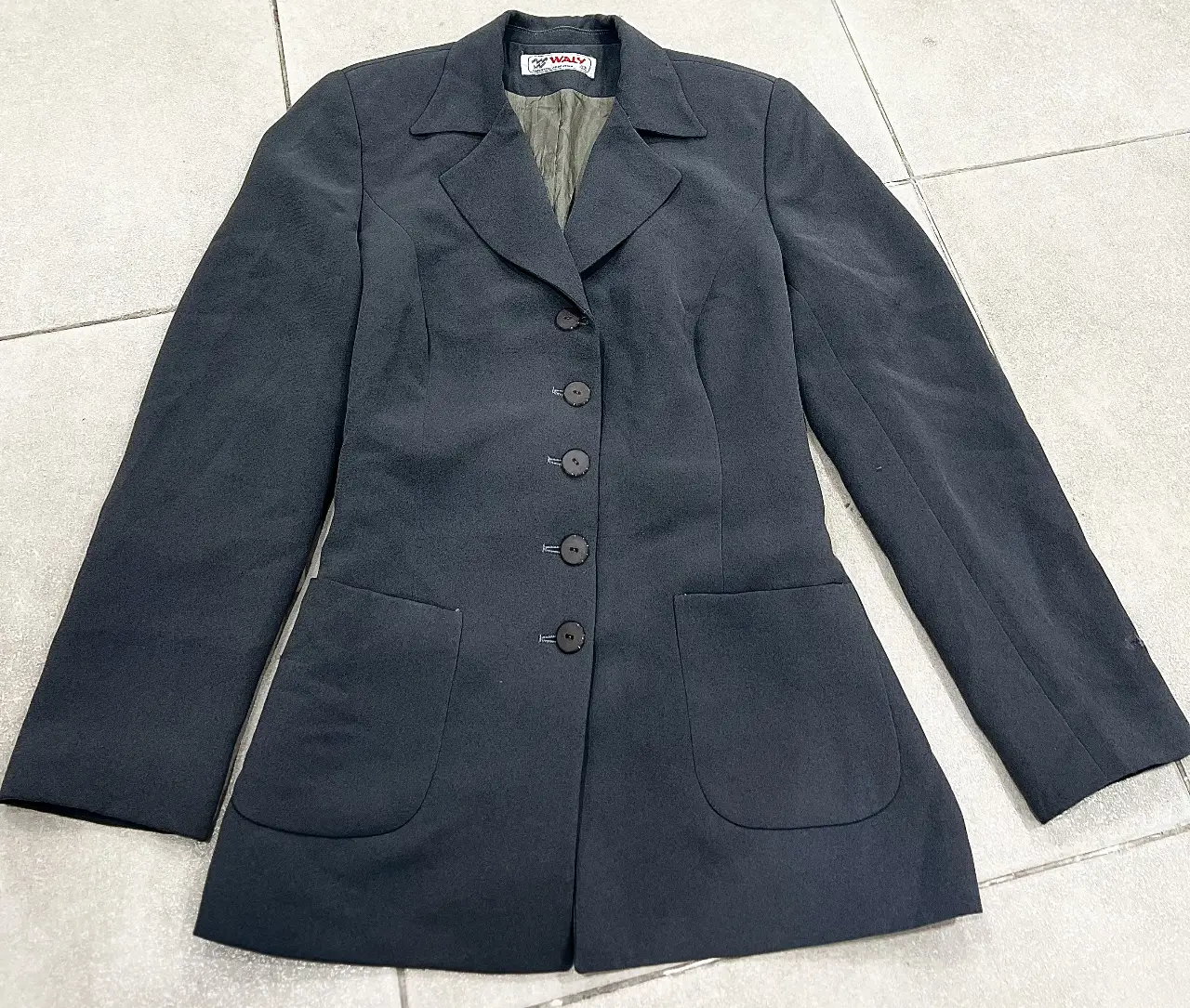 Elegante blazer de mujer, color gris oscuro, con cuatro botones frontales y dos bolsillos delanteros. Ideal para un look formal o de trabajo. con cinto ajustable en cintura 