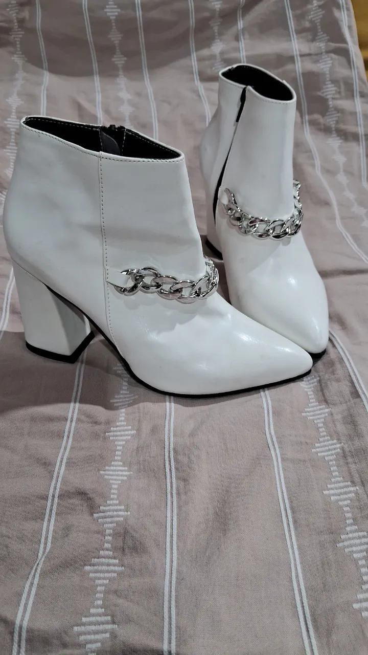 Botitas blancas con taco y detalle de cadena plateada. Un diseño moderno y canchero para lucir en cualquier ocasión.