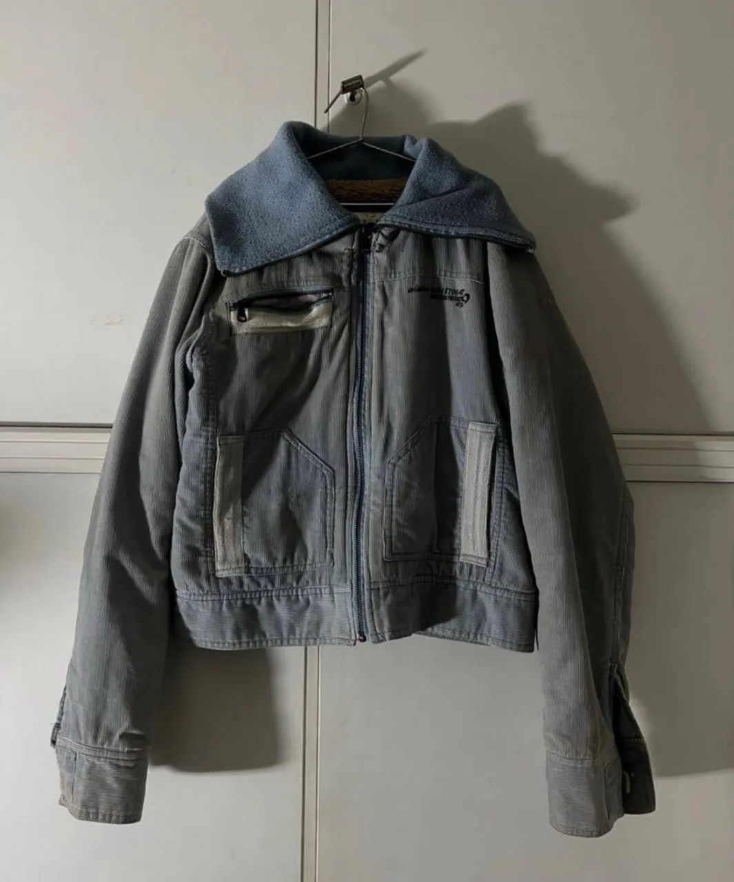 Campera de pana con cuello de tejido. Cierre al frente y bolsillo superior con cierre. Puños con botones.