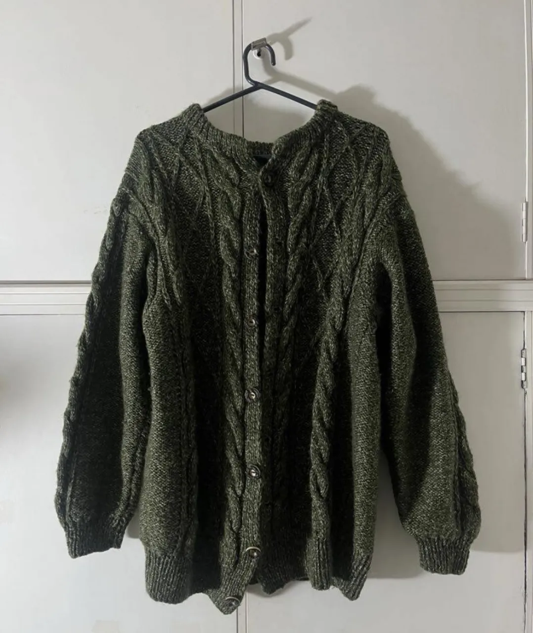 Cardigan de tejido grueso con botones al frente. Presenta un diseño de trenzas en toda la prenda.