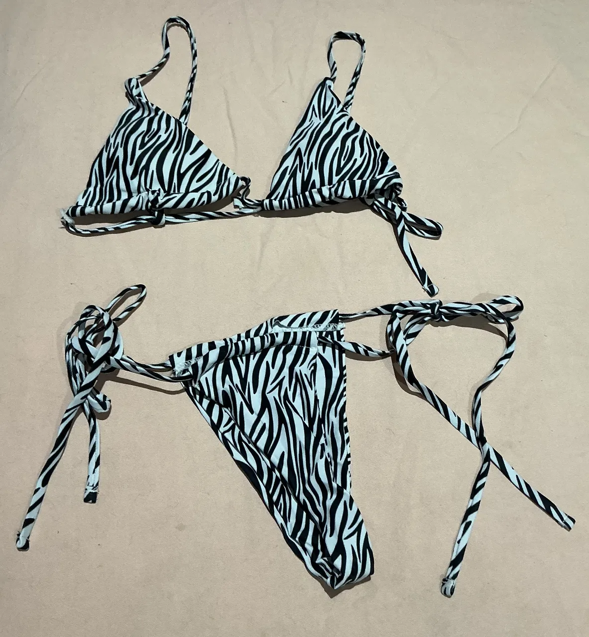 Conjunto de bikini estampado cebra, con corpiño triangular y bombacha colaless. Ambos con tiras regulables para atar.