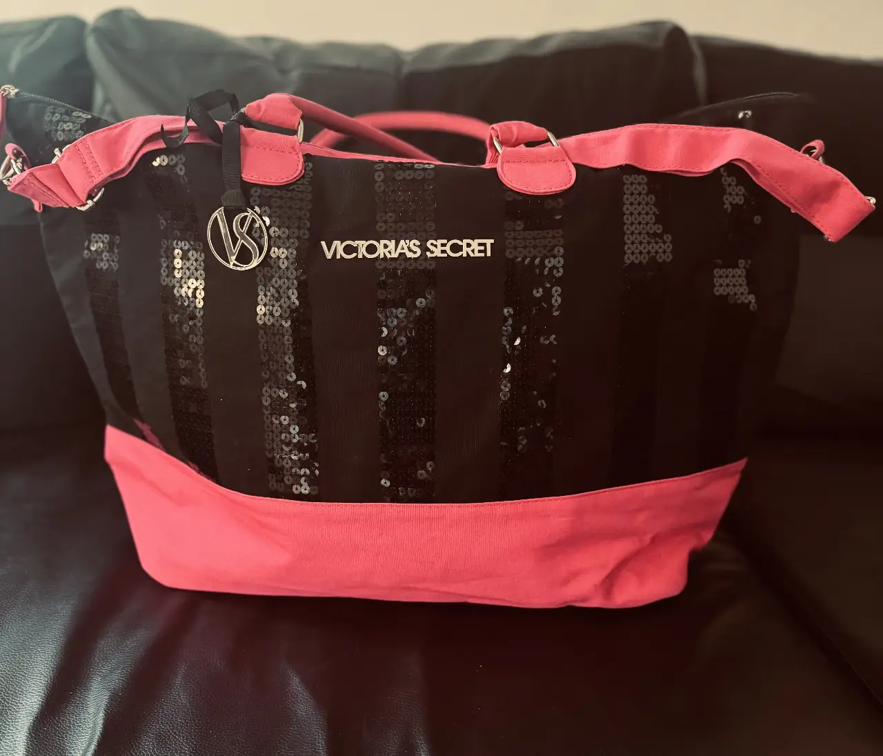 Bolso Victoria's Secret negro con lentejuelas y detalles en rosa. Ideal para llevar todo lo necesario con estilo.