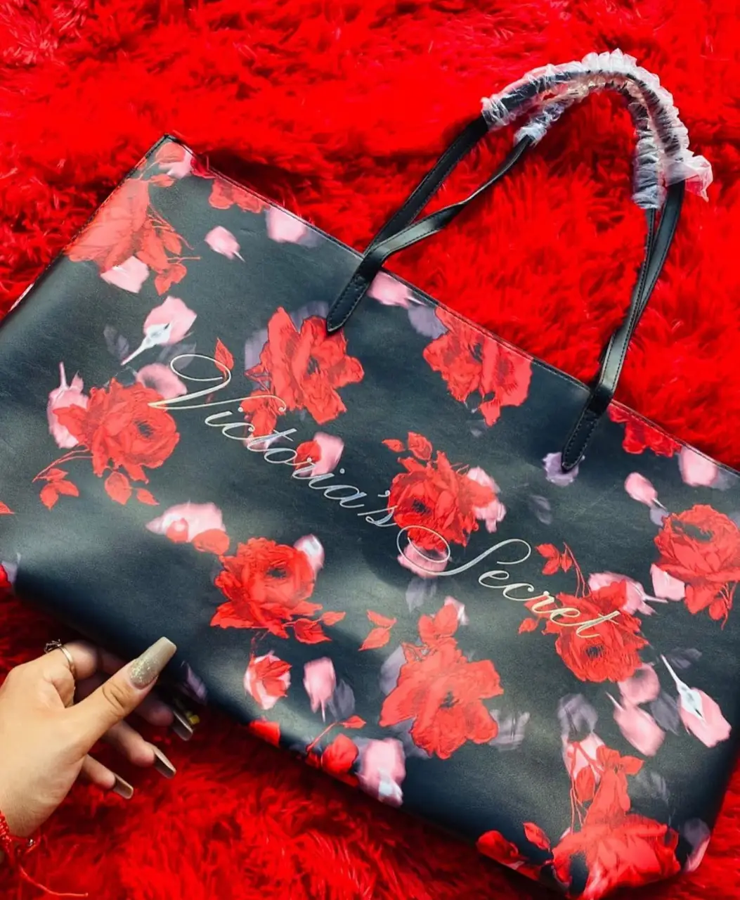 Bolso tote de Victoria's Secret con estampado floral en rojo sobre fondo negro. Ideal para llevar todo lo que necesitas con estilo.