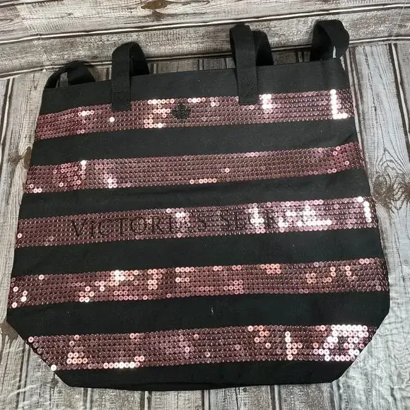 Bolso tote negro con franjas horizontales de lentejuelas rosas. Ideal para llevar tus pertenencias con estilo y un toque de brillo.