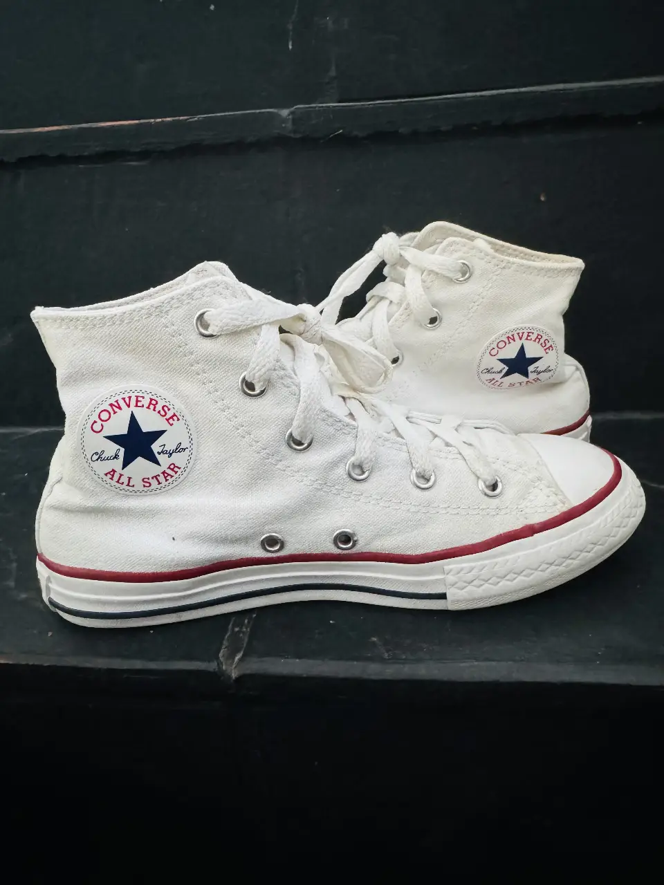 Zapatillas Converse All Star blancas de lona, con detalles en rojo y azul marino. Ideales para un look casual y urbano.